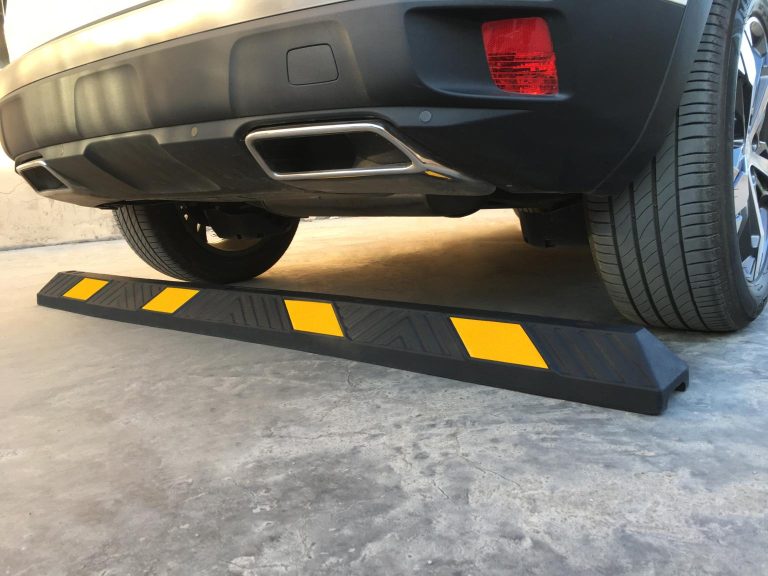 A black and yellow parking kerb with reflective glass beads placed behind the wheels