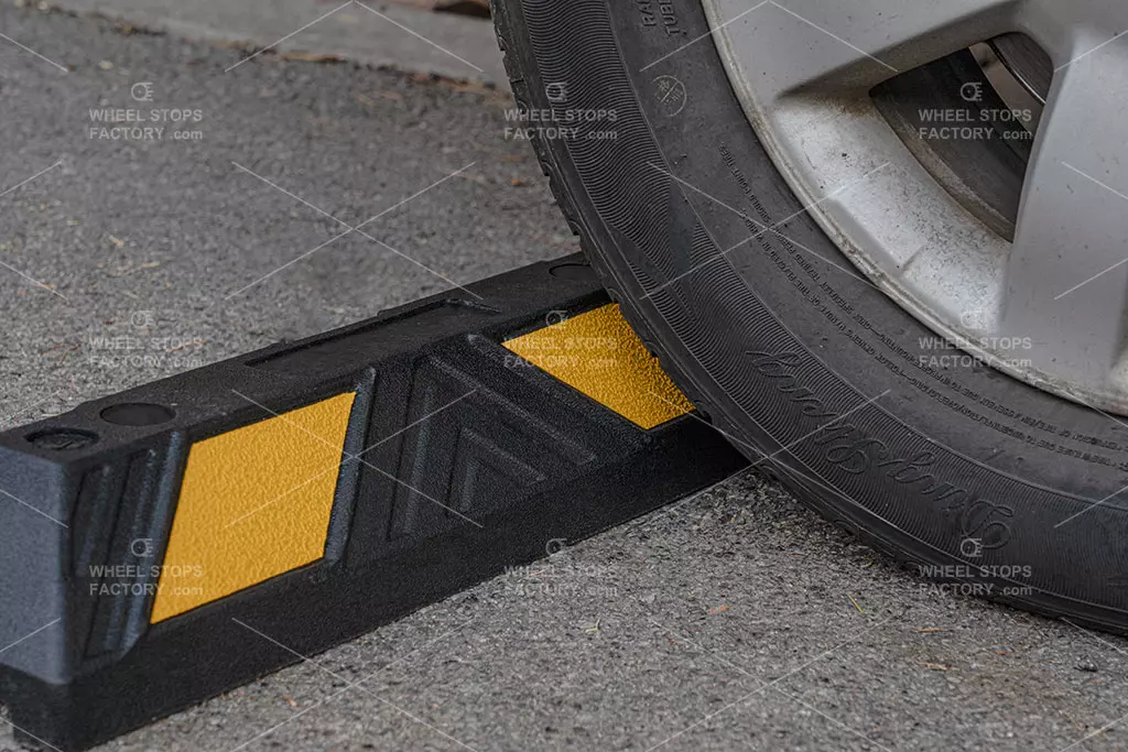 A yellow and black wheel stopper installed in the parking lot used as a parking tool