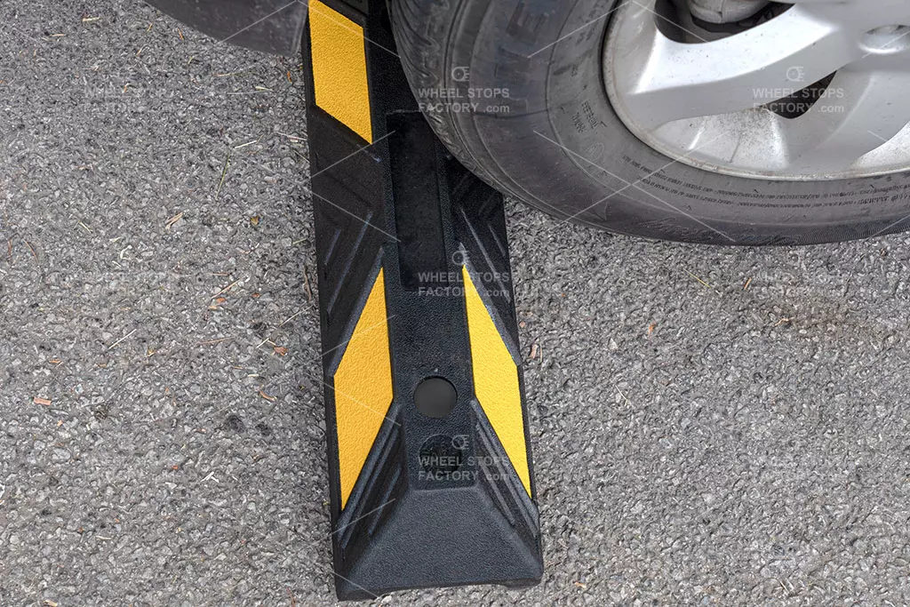 A black and yellow parking stop against the car tyre in the hotel parking area