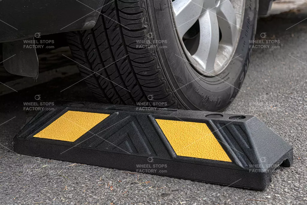 Black and yellow parking blocks against the car tyre, used as traffic safety tools