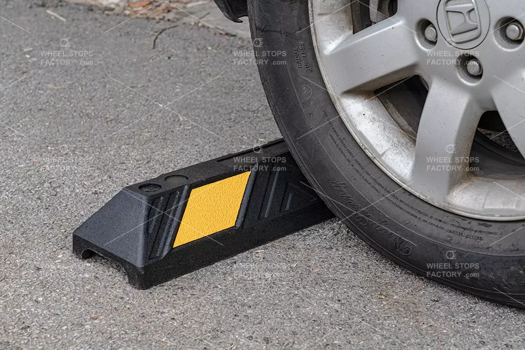 A black and yellow wheel stop against a car wheel in the parking area