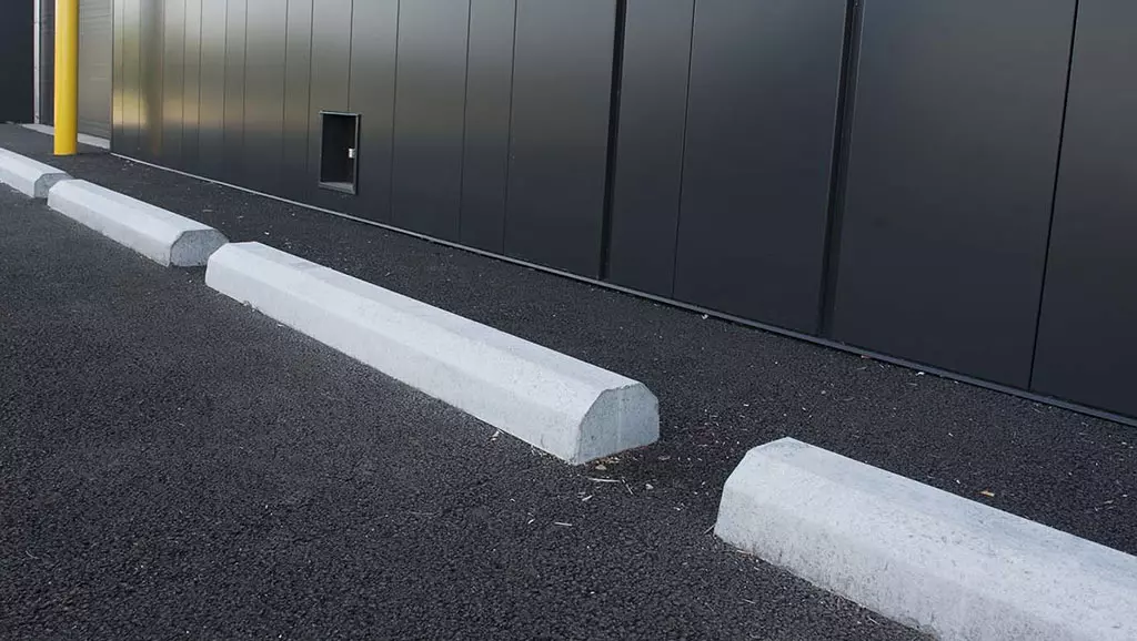 A group of white precast concrete wheel stops installed in the parking lot