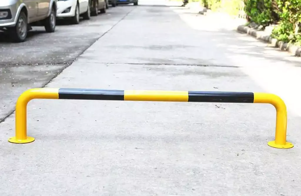 A yellow and black metal wheel stopper is placed on the cement ground