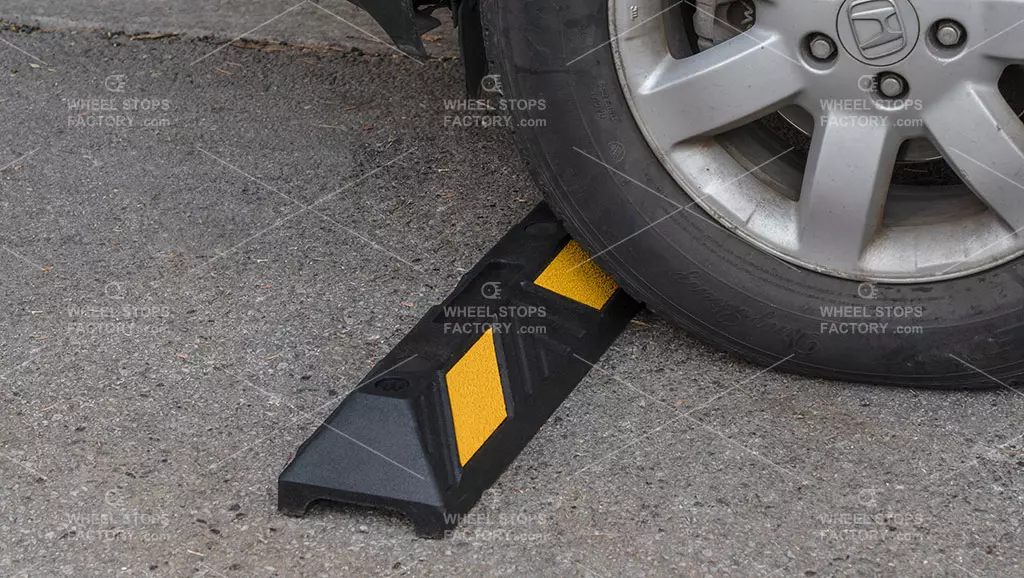 Parking hall car stops placed near a car wheel on the asphalt ground