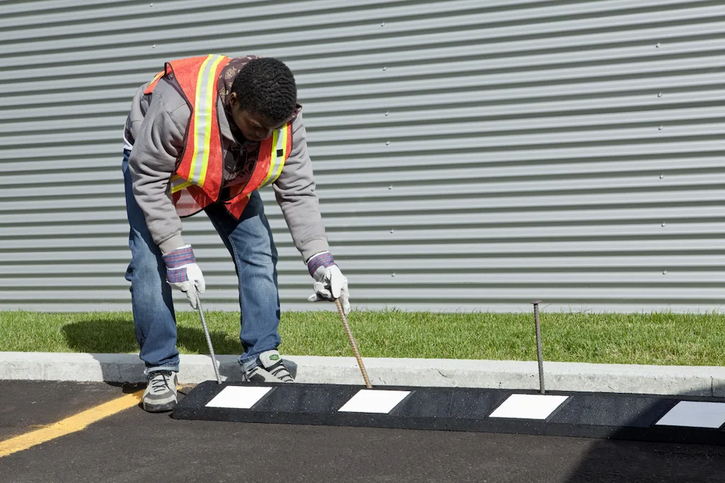 A man is installing a black parking block with white reflective films.